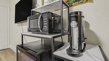 A kitchen with a microwave, coffee maker, and a small refrigerator.