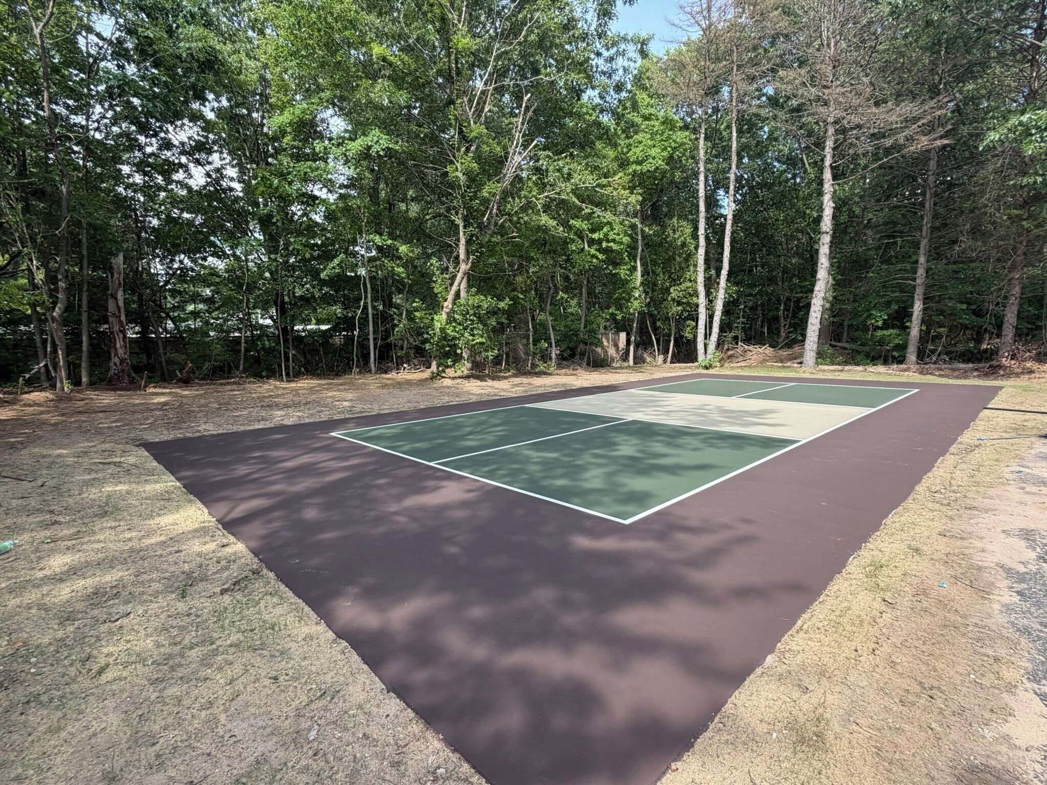 An outdoor tennis court surrounded by trees.