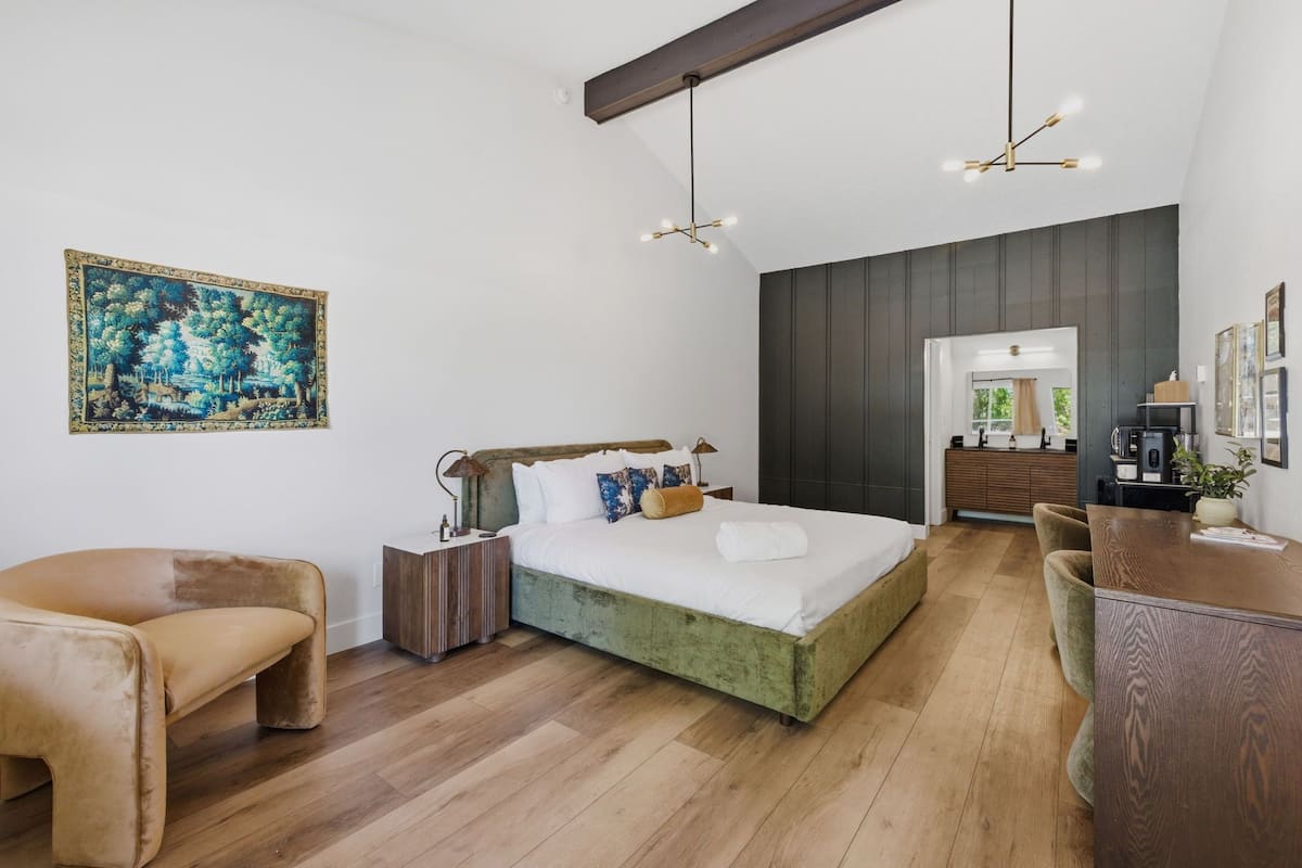 Un dormitorio moderno con una cama grande, mesitas de noche, un escritorio y una silla.