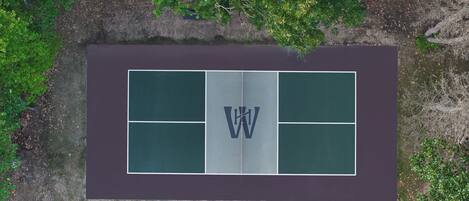 An aerial view of a tennis court with a logo in the center.