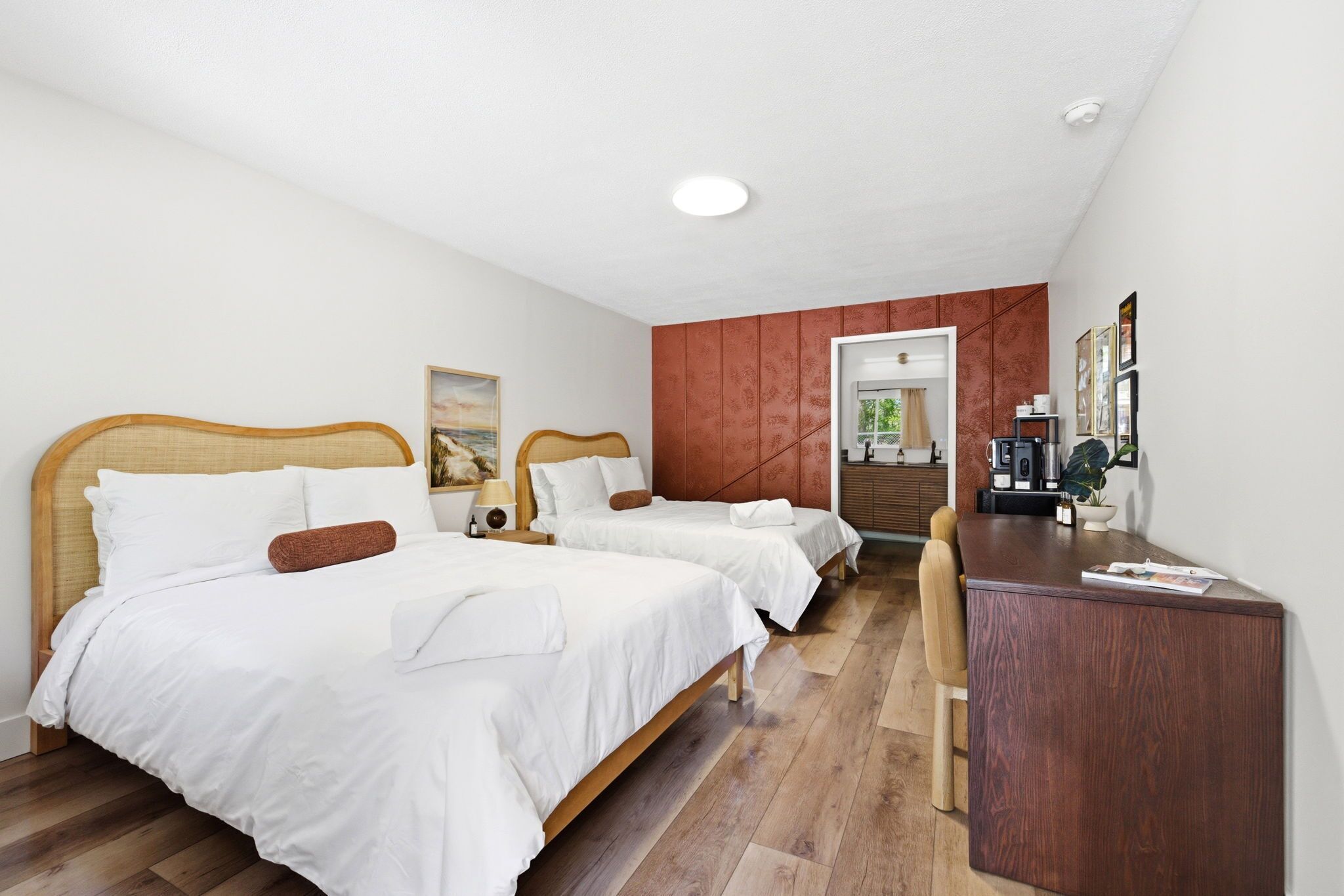 Una habitación de hotel con dos camas, un escritorio y una puerta que da a un baño.