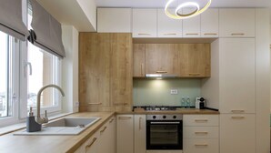 A modern kitchen with wooden cabinets, a gas stove, an oven, and a window with a view. - Cozy & Modern Apartment Near Arena Mall, Free Parking, Wi-Fi ,Ac. (Bacau)