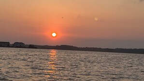 A sunset over a body of water with a distant shoreline.