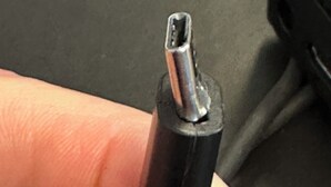 A close-up of a metallic object with a pointed tip, held by a finger.