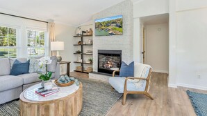A living room with a fireplace, a sofa, a chair, a coffee table, and a bookshelf. - Lakefront Retreat w/ Boat Dock, Hot Tub & Large Game Room!  Sleeps 10 (Denver)