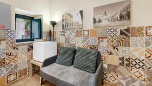 A room with a sofa, a window, and patterned tiles on the walls.
