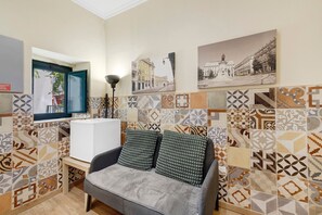 A room with a sofa, a window, and patterned tiles on the walls. - Tiny gem in the heart of Alfama (Lisboa)