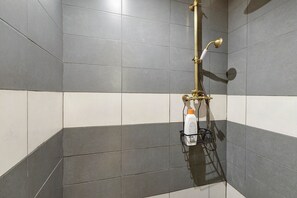 A shower with a handheld showerhead, a bottle of shampoo, and a towel rack. - Tiny gem in the heart of Alfama (Lisboa)