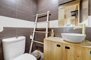 Een badkamer met een toilet, een houten kastje met een wastafel en een spiegel.