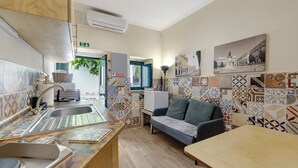 A kitchen with a sink, a refrigerator, and a dining area with a table and a sofa.