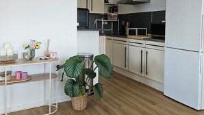 Uma cozinha moderna com armários brancos, um exaustor de aço inoxidável e uma geladeira branca.