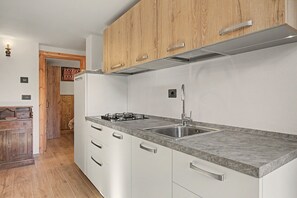 Une cuisine moderne avec des meubles blancs, un évier en acier inoxydable et une cuisinière à gaz.