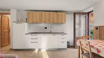 A compact kitchen with wooden cabinets, a gas stove, and a sink.