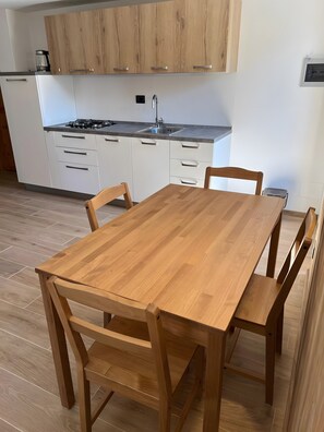 A modern kitchen with white cabinets, a wooden dining table, and a built-in stove.