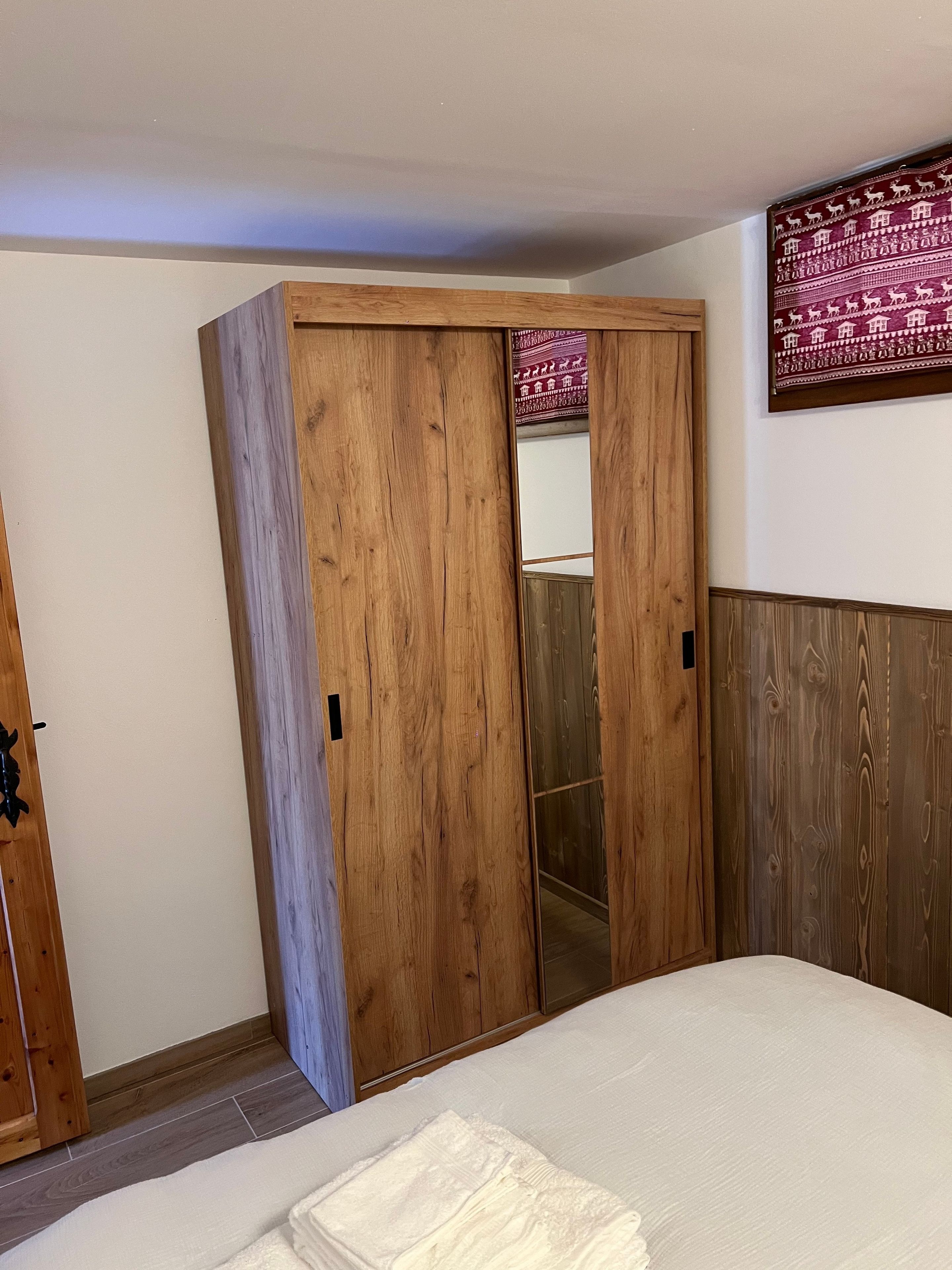 Un dormitorio con un amplio armario de madera, una cama con ropa blanca y una obra de arte colgada en la pared.