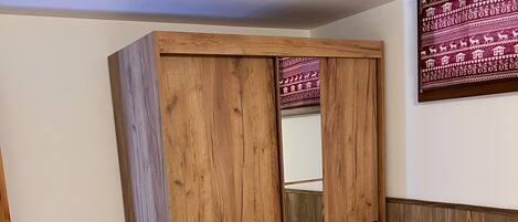 Un dormitorio con un amplio armario de madera, una cama con ropa blanca y una obra de arte colgada en la pared.