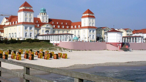 Ein großes, historisches Gebäude mit mehreren Türmen und einer markanten Kuppel, gelegen am Sandstrand.