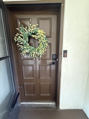 A brown door with a wreath, a doorbell, and a doorbell button. - Newly renovated 2-bedroom, 2-bathroom condo located in sunny Sarasota, Florida. (Sarasota)