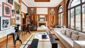 A spacious living area with a fireplace, large windows, and artwork on the walls. - Par056 - Mansion-Style Apartment by Parc Monceau (Paris)