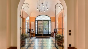 A hotel lobby with a checkered floor, mirrored walls, a chandelier, and a large arched doorway. - Par056 - Mansion-Style Apartment by Parc Monceau (Paris)