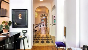 A hallway with a checkered floor, framed artwork on the walls, and a desk with a chair. - Par056 - Mansion-Style Apartment by Parc Monceau (Paris)
