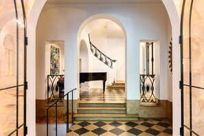 Eine prächtige Treppe mit Schachbrettmuster führt zu einem Klavier in einem großzügigen Raum.