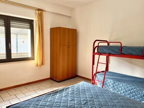 A room with a bunk bed, a wooden wardrobe, and a window with curtains. - Familiar Apartment Close to the Beach (Lignano Sabbiadoro)