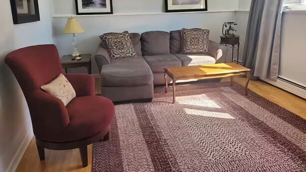 Una sala de estar con un sillón rojo, sofá gris y una mesa de centro de madera.