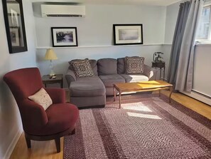 A living room with a red armchair, grey sofa, and a wooden coffee table.