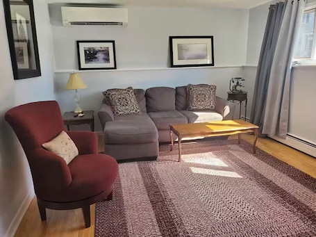A living room with a red armchair, grey sofa, and a wooden coffee table.