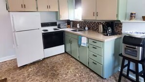 Una cocina con refrigerador, estufa, pileta y una pequeña mesada con cafetera.