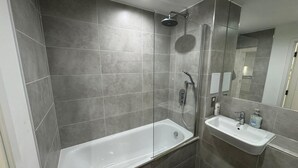 Et moderne badeværelse med badekar, bruser og vask.