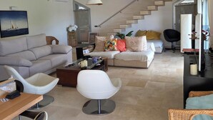 Uma sala de estar moderna com um sofá, cadeiras, uma mesa de centro e uma escada.