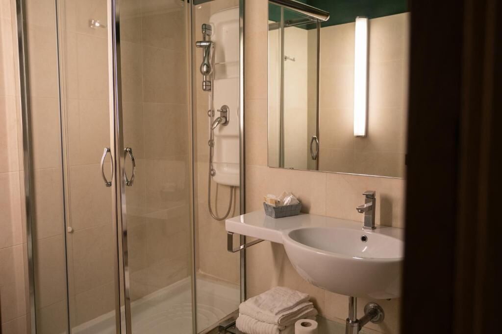 A modern bathroom with a glass shower enclosure, a white sink, and a mirror.