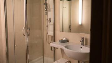 A modern bathroom with a glass shower enclosure, a white sink, and a mirror.
