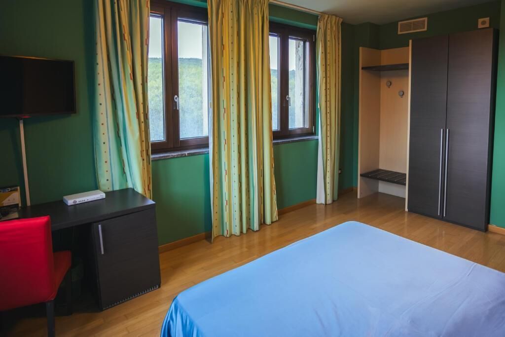 A room with a bed, a desk, a chair, a wardrobe, and a shower area.