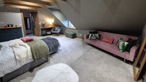 A loft bedroom with a bed, a pink sofa, a chair, and a desk. - Fabulous 4-bedroom 2.5 bathroom cottage in charming Paisley / Glasgow (Paisley)