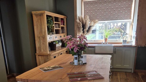 A kitchen with a wooden island, a window with a view, and a wooden cabinet with glassware. - Fabulous 4-bedroom 2.5 bathroom cottage in charming Paisley / Glasgow (Paisley)