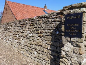 Een stenen muur met een bord waarop staat 'ALLEEN BEWONERS VAN SNEATON HALL'.
