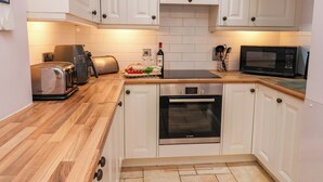 Eine moderne Küche mit weißen Schränken, einem Bosch-Ofen, einem Toaster, einer Mikrowelle und einem Schneidebrett mit Brot und Tomaten.