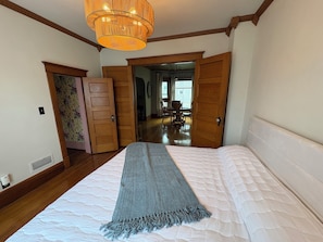 Un dormitorio con cama, una puerta de madera, un pasillo y una zona de comedor.