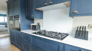 A kitchen with blue cabinets, a white countertop, and a gas stove. - Pengarnedd (Amlwch)