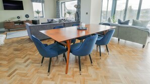 A modern living space with a dining area, sofa, and large windows. - Pengarnedd (Amlwch)