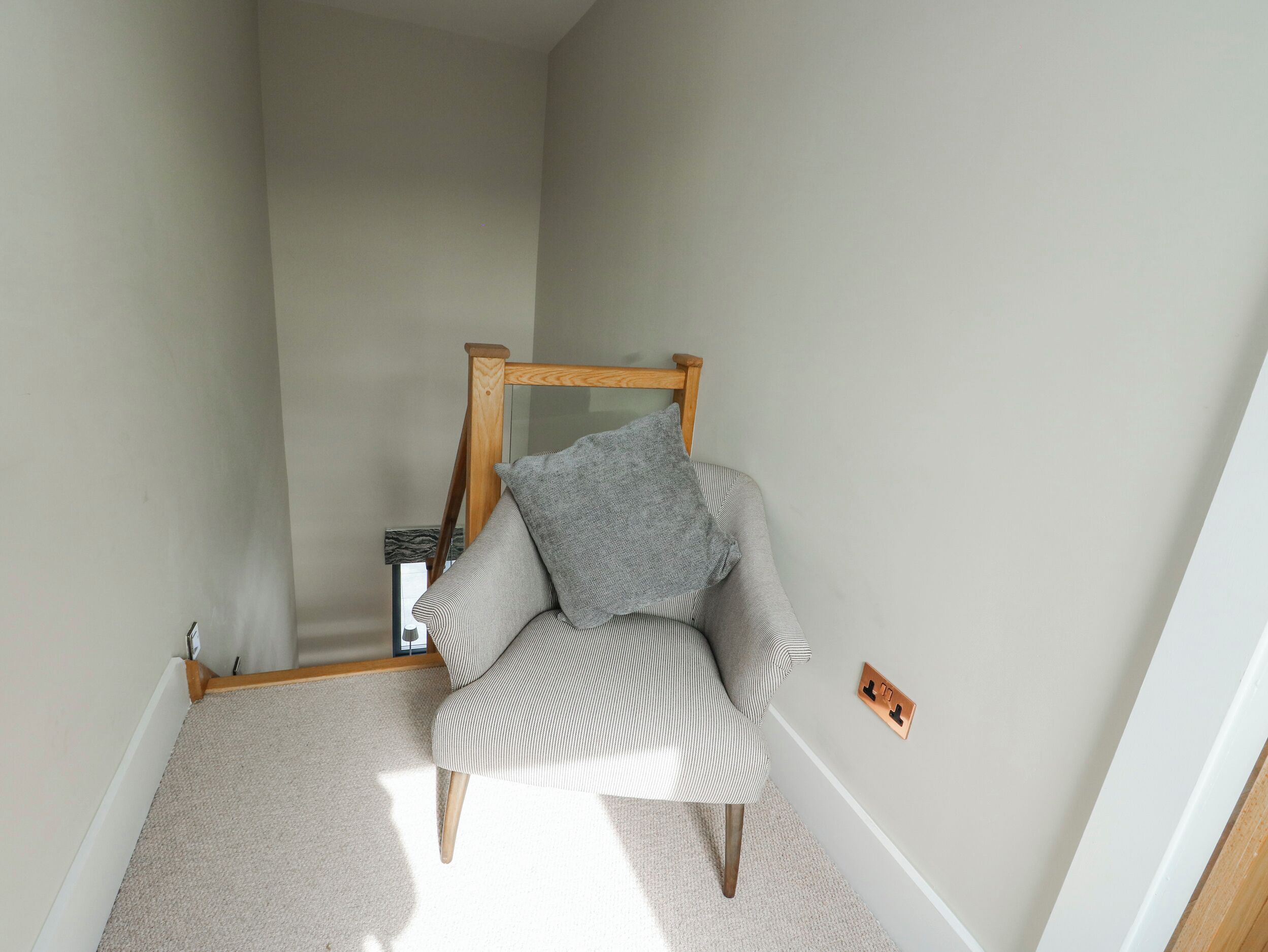 A corner room with a chair, a small table, and a wall-mounted mirror.