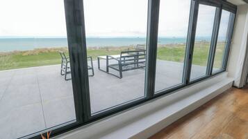 Una habitación con ventanas amplias que dan a un área verde y al mar.