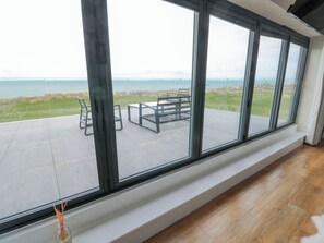 Una habitación con ventanas amplias que dan a un área verde y al mar.