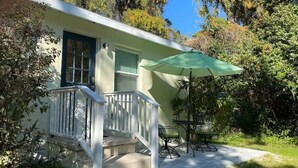 Una casa con porche, una mesa y sillas, y un paraguas verde.