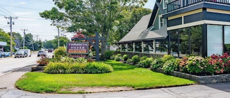 A Yarmouth House with a signboard, a grassy lawn, and a building with a balcony.