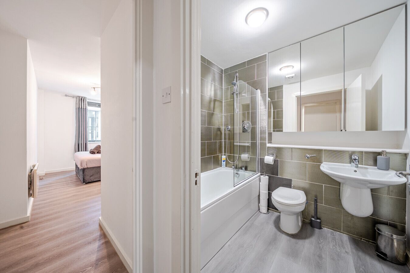 A modern bathroom with a glass shower enclosure, a white toilet, and a sink.