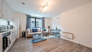 Een modern appartement met een kitchenette, een bank, een eettafel en een radiator.
